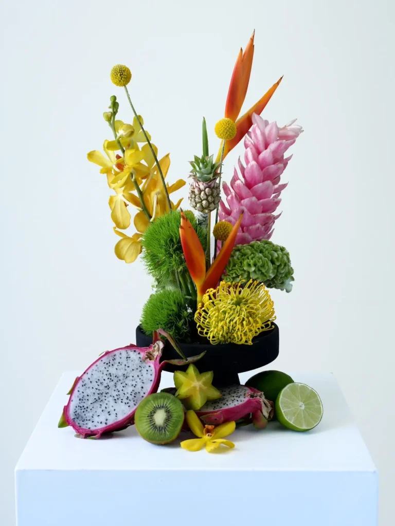 Tropical floral arrangement styled with dragon fruit, kiwi, starfruit, and lime