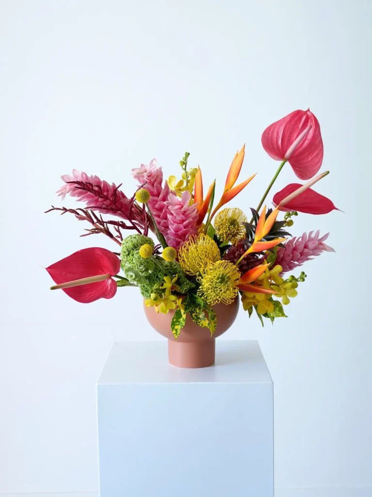 Close-up of tropical arrangement with pink ginger, yellow pincushion protea, and red anthurium